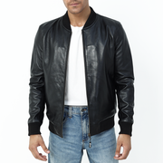 A man wearing a black bomber motorcycle jacket with a standing collar, zipper details, and front pockets.
